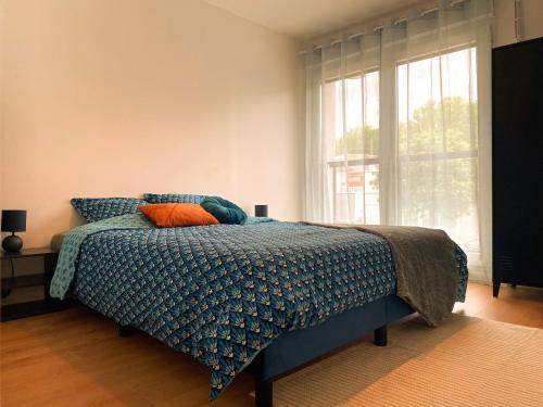 a bedroom with a bed with a blue comforter and a window at Le Refuge Urbain in Villejuif