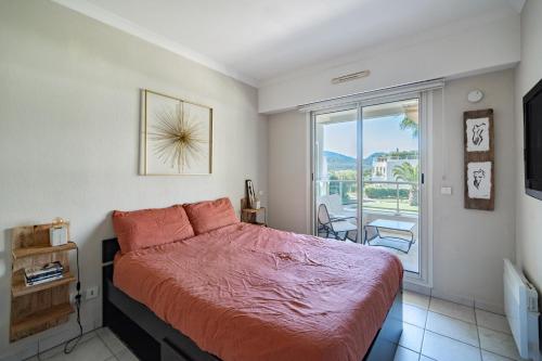 une chambre avec un lit et une grande fenêtre dans l'établissement Appartement au Riviera Golf Domaine de Barbossi, à Mandelieu-la-Napoule