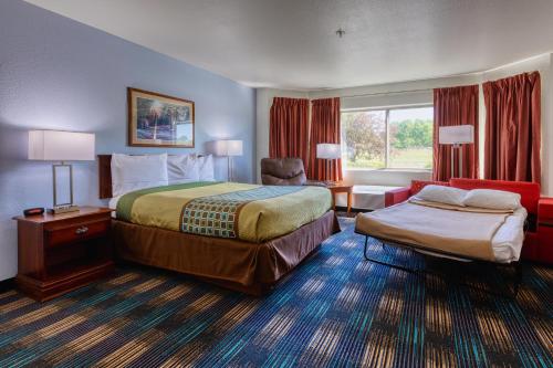 ein Hotelzimmer mit zwei Betten und einem Stuhl in der Unterkunft All Towne Suites in Saint Robert