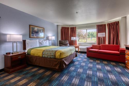 a hotel room with a bed and a red couch at All Towne Suites in Saint Robert