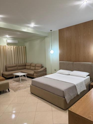 Un dormitorio con una cama grande y un sofá. en Hotel Kaloshi, en Tirana