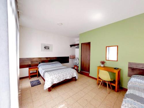 a bedroom with two beds and a table and a desk at H. Galaxia in Oaxaca City