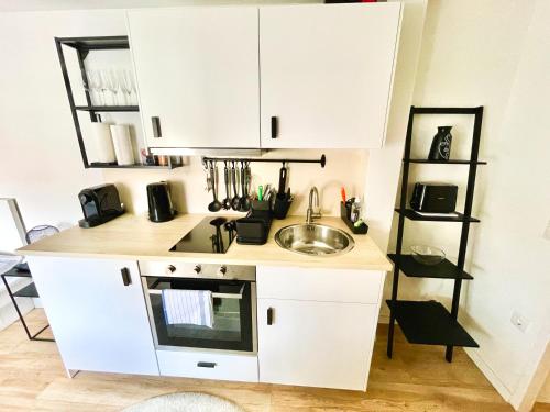 een kleine keuken met witte kasten en een wastafel bij StayHere Central City Studio 18 - contactless Self-Check-IN in Graz
