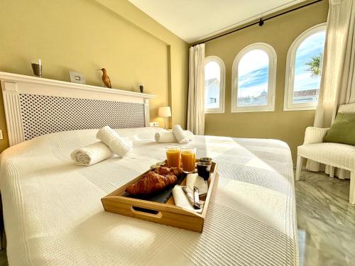 Una cama blanca con una bandeja de comida. en Diletta Beach Estepona, en Estepona