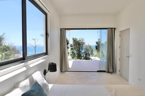een witte slaapkamer met een groot raam en een bed bij Les Roches - Paradise Retreat in Santa Teresa Beach