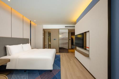 a bedroom with a white bed and a flat screen tv at Holiday Inn Express Suzhou Bay by IHG in Suzhou