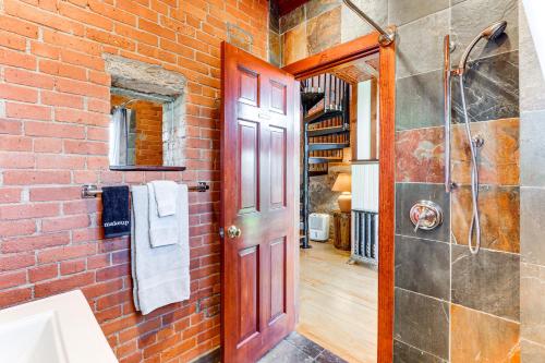 a brick bathroom with a shower and a red door at Downtown Essex Apartment - Steps to River! in Essex