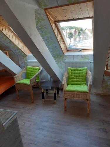 two chairs with green cushions in a room with stairs at Apartments zum Brauergang in Garz-Rügen