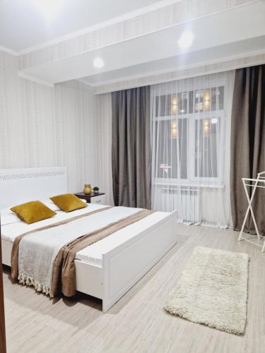 a white bedroom with a large bed and a window at 17 мкр 46 дом ЖК Мерет 2 этаж, недалеко от моря in Aktau