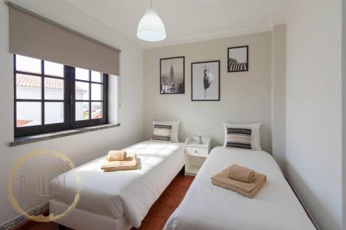 two beds in a room with white walls and windows at Baleal Classic Waves Guest House in Baleal