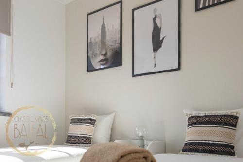 a bedroom with a white bed with pictures on the wall at Baleal Classic Waves Guest House in Baleal