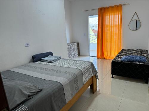 a bedroom with two beds and a window with an orange curtain at Linda Casa com piscina Brisa do Mar - Maragogi in Maragogi