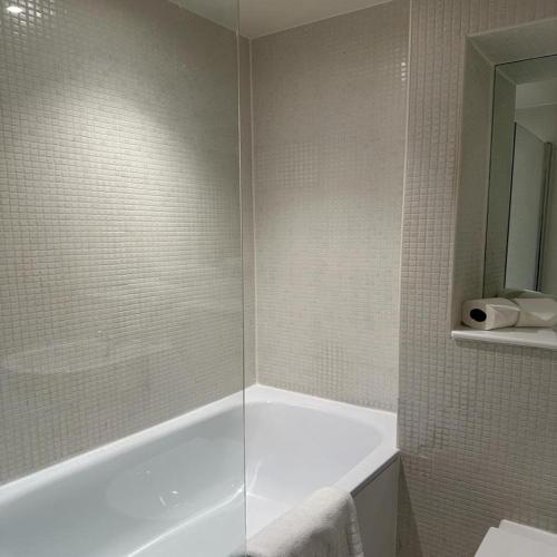 a bathroom with a shower with a tub and a sink at Canary Wharf - Luxury Apartments in London