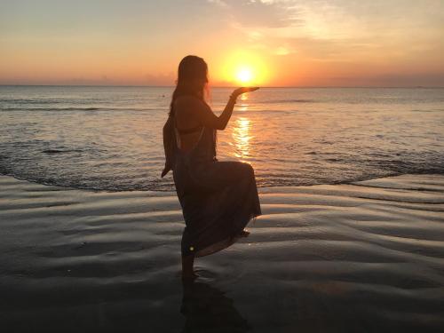 a woman is standing on the beach at sunset at Studio at the Beach in Ban Ao Makham