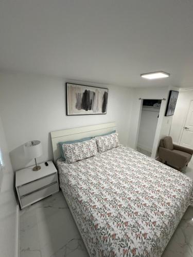 a white bedroom with a bed and a chair at Adrien Guest Studio in Miami Gardens
