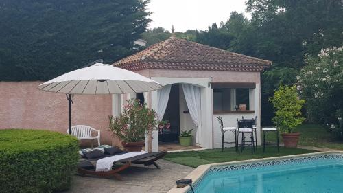 une maison avec une piscine et un parasol dans l'établissement La Villa Bella, à Beauvoisin
