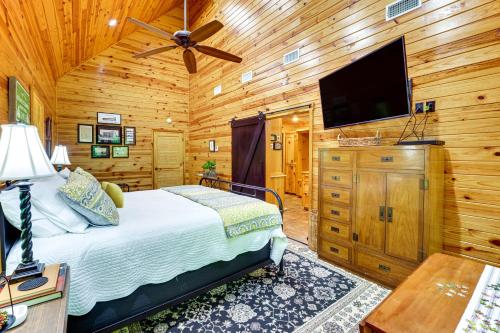 a bedroom with a bed and a flat screen tv at Riverfront Cabin with Outdoor Oasis in Seminary! in Collins