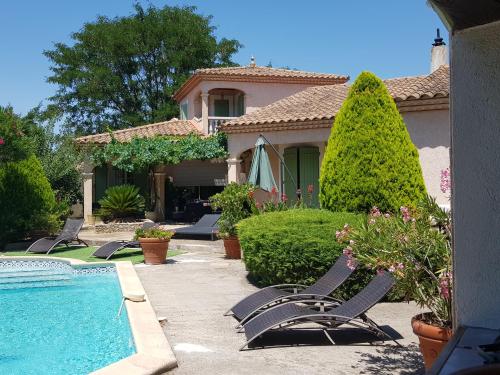 une maison avec des chaises et une piscine dans une cour dans l'établissement La Villa Bella, à Beauvoisin