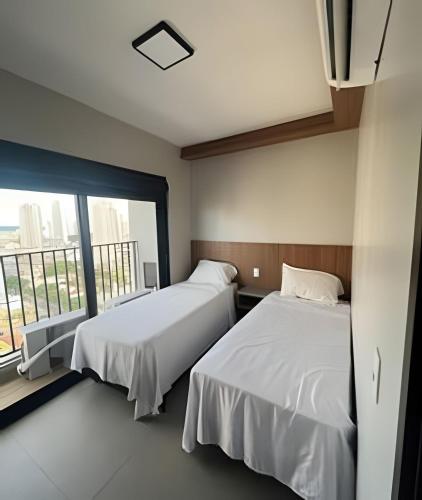 two beds in a room with a large window at Boutique Bueno / Apto de luxo in Goiânia