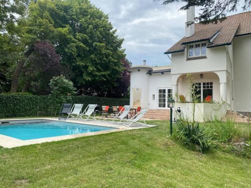 une cour avec une piscine et des chaises et une maison dans l'établissement VILLA TOUQUETTOISE HELAND , 4 Étoiles , piscine chauffée, à Le Touquet-Paris-Plage