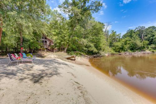a couple of chairs sitting on a beach next to a river at Riverfront Cabin with Outdoor Oasis in Seminary! in Collins