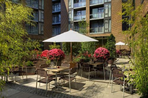 a patio with tables and chairs and an umbrella at Adina Apartment Hotel Copenhagen in Copenhagen