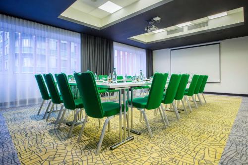 een vergaderzaal met een tafel en groene stoelen bij Park Inn by Radisson Bucharest Hotel & Residence in Boekarest
