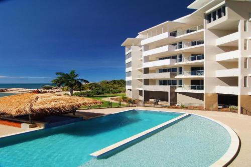 a swimming pool in front of a hotel at Coral Cove Apartments in Bowen