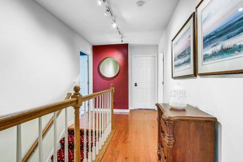 a hallway with a staircase with a red accent wall at Menasha Home with Patio - Walking Distance to Lake! in Menasha