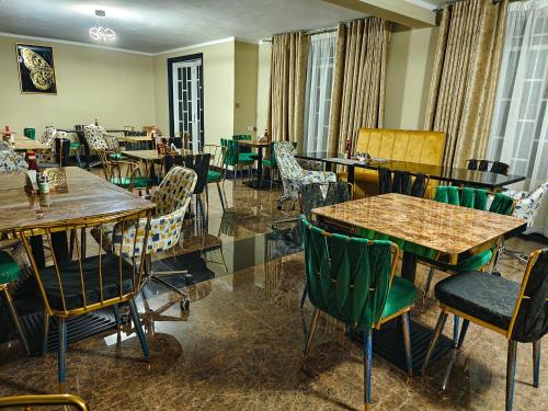 un restaurante con mesas y sillas de madera y ventanas en Annavilla7 Lilongwe Aparthotel, en Lilongwe
