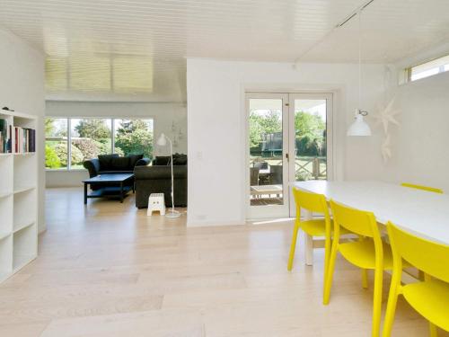 a living room with a dining room table and yellow chairs at 6 person holiday home in Gilleleje-By Traum in Gilleleje
