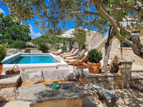 a backyard with a swimming pool with chairs and a table at Villa Žurnata in Bogomolje