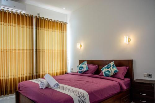 um quarto com 2 camas e lençóis roxos em Turtle House Lombok em Kuta