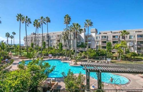 vista para uma piscina num resort com palmeiras em Oceanview Retreat - Steps to the Beach and 2 Pools em Oceanside