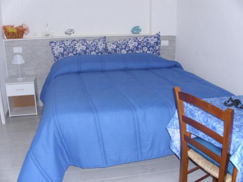 a blue bed with a blue comforter and a wooden chair at Affittacamere Cecilia in Castellammare del Golfo