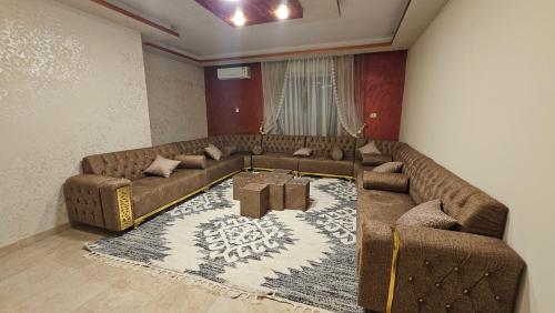 a living room with a large couch and a rug at Luxurious Apartment in Tabrbour شقة فخمة بطبربور in Amman
