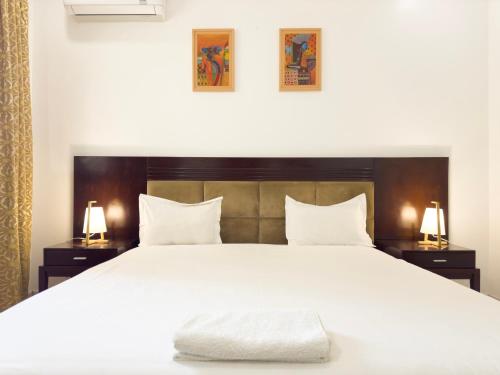 Un dormitorio con una gran cama blanca con dos lámparas. en Oasis, Seaside, en Dakar