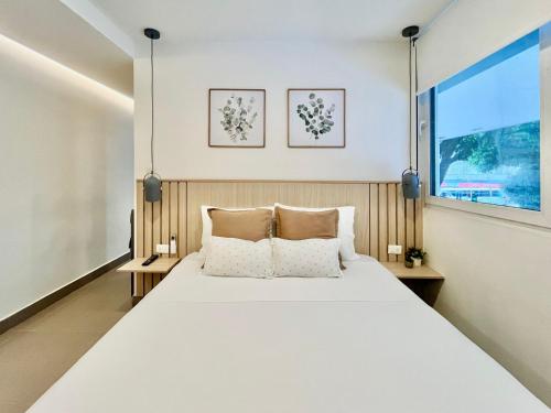 Reset Hotel & Café (Apartamento 201) في كالي: غرفة نوم بسرير ابيض كبير مع وسادتين