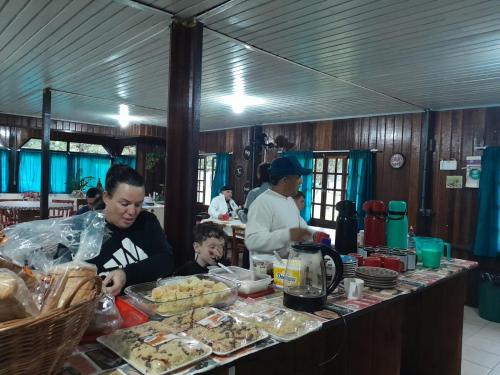 a woman and a man preparing food in a kitchen at Hostel e Pousada Araquari in Paraty