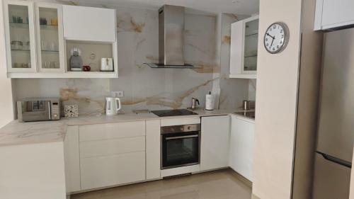 una cucina con armadi bianchi e un orologio sul muro di Apartamento corazon de Canteras a Las Palmas de Gran Canaria