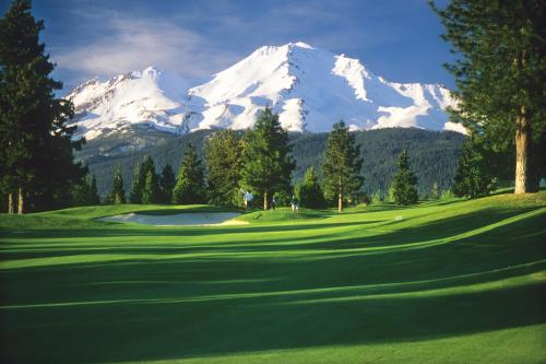 a golf course with a snow covered mountain in the background at Mount Shasta Resort in Mount Shasta
