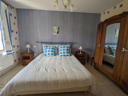 a bedroom with a large bed with blue pillows at Charmant gîte historique avec terrasse, salle de jeux, et recharge électrique – proche Vittel & Contrexéville - FR-1-589-219 in Serocourt