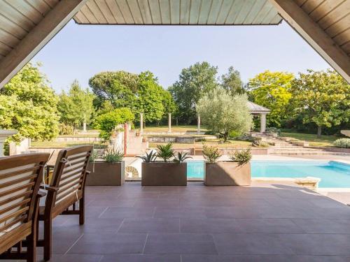 un patio avec deux bancs et une piscine dans l'établissement Gîte authentique avec piscine chauffée et jardin paysager près de Nantes - FR-1-306-962, à Saint-Étienne-de-Montluc