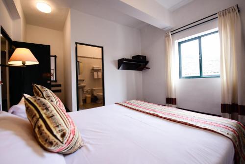 Un dormitorio con una cama blanca con almohadas y una ventana en Hotel Raymi, en Cusco