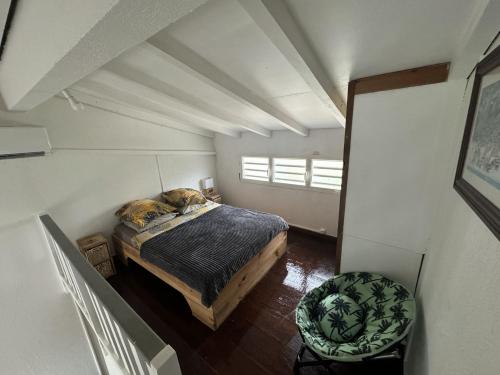 a bedroom with a bed and a chair in a room at Duplex piscine vue imprenable Marina du Gosier avec citerne in Le Gosier