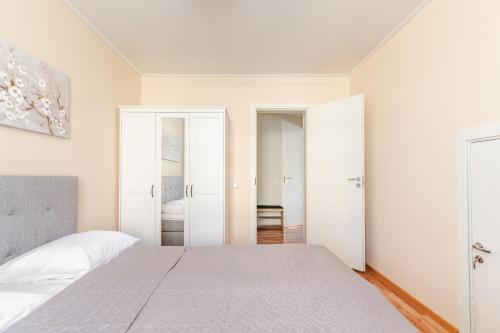 a white bedroom with a bed and two open doors at Liidia Apartments in Haapsalu