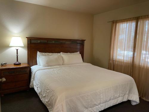 a bedroom with a white bed with a lamp and a window at Mount Shasta Resort in Mount Shasta