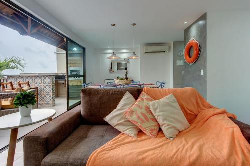 sala de estar con sofá y manta naranja en Cobertura Duplex Jacuzzi - Mediterranee Residence, en Aquiraz