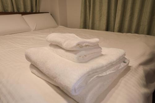 een stapel witte handdoeken zittend op een bed bij SL601, 山手線-新宿2分, 5mins walk from shinokubo station free wifi in Tokyo