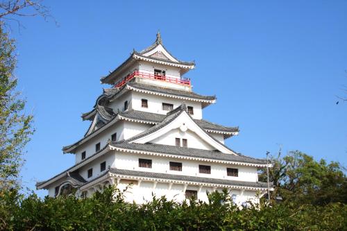 a tall white building with a roof on top of trees at 城下町に佇む癒しの宿 旅館 大政 in Karatsu